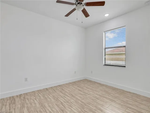 an empty room with a window and a ceiling fan