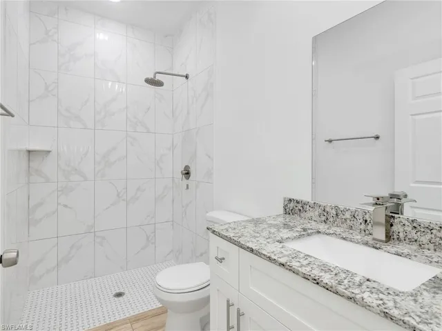 a bathroom with a granite countertop sink a toilet and shower