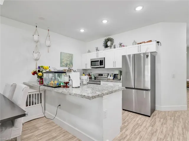 a kitchen with granite countertop a refrigerator a stove a microwave and cabinets