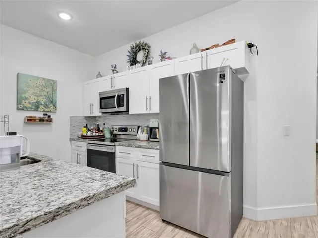a kitchen with stainless steel appliances granite countertop a refrigerator stove microwave and sink