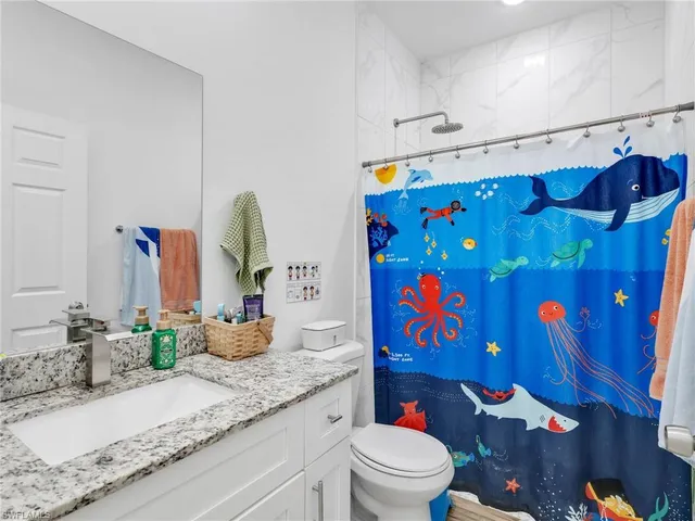 a bathroom with a granite countertop sink a toilet and a shower