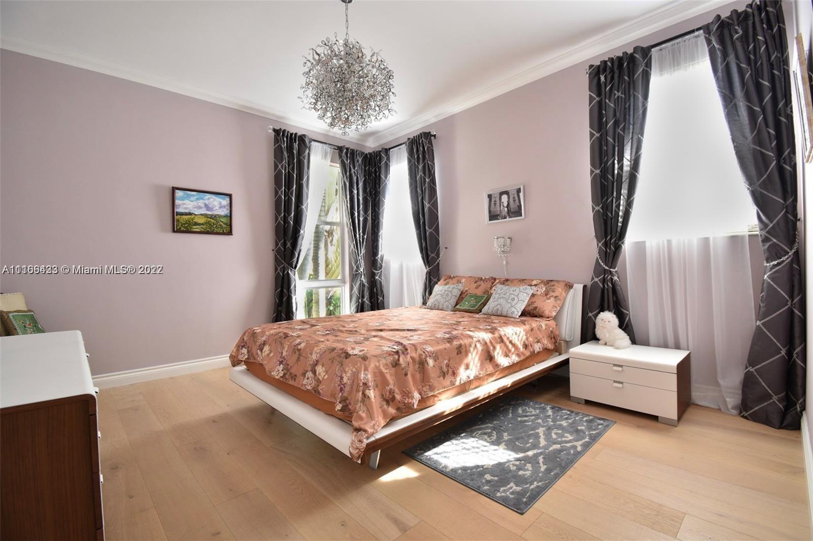 9033 Byron Avenue Surfside, FL 33154 - Photo 22 of 25 a bedroom with a bed and a chandelier
