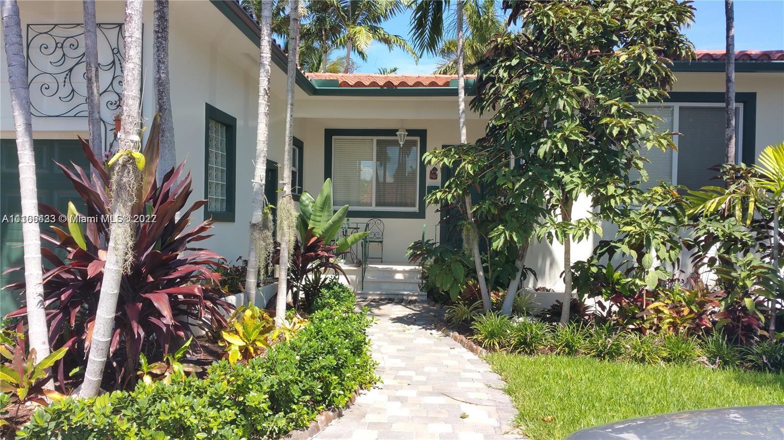 9033 Byron Avenue Surfside, FL 33154 - Photo 5 of 25 a front view of a house with a flower garden