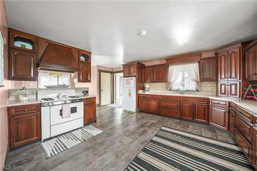 9561 Creaser Road North Bloomfield, OH 44450 - Photo 2 of 45 Kitchen with white appliances, light countertops, decorative backsplash, dark wood-style floors, and a textured ceiling