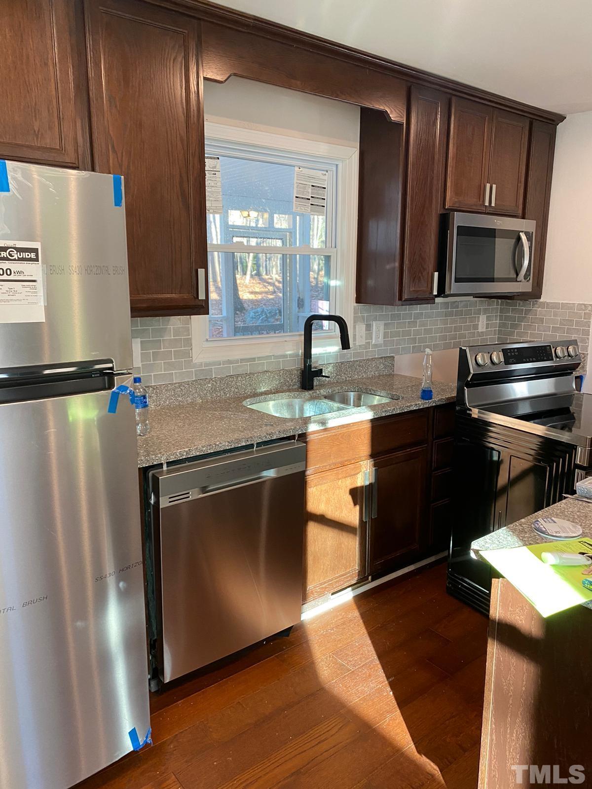 5907 Scalybark Road Durham, NC 27712 - Photo 2 of 3 a kitchen with granite countertop stainless steel appliances a sink a refrigerator a stove a microwave and cabinets