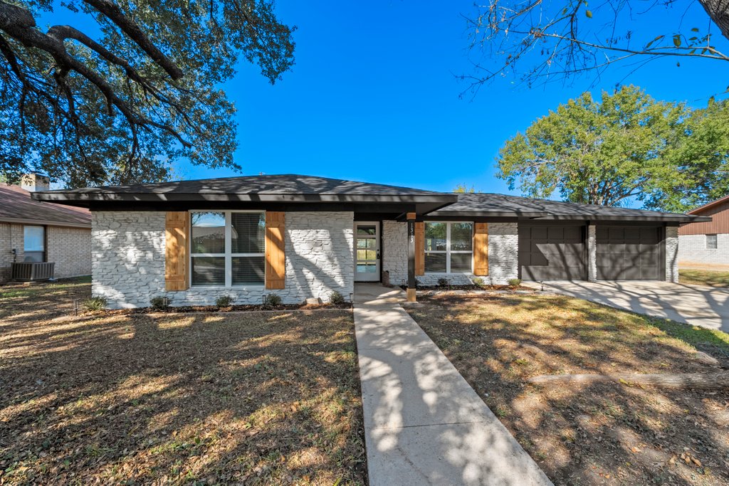View of front facade featuring driveway, an attached garage, and brick siding