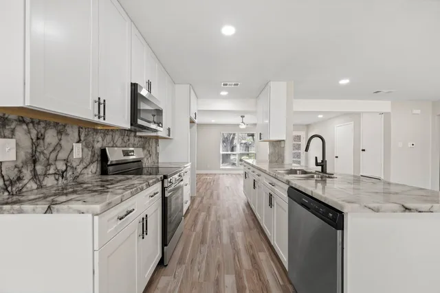a kitchen with stainless steel appliances granite countertop a sink stove and cabinets
