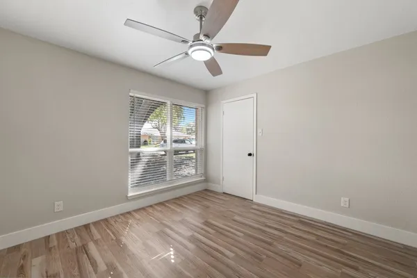an empty room with wooden floor fan and windows