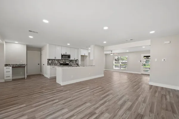 a view of kitchen with kitchen island granite countertop a stove top oven a sink and a refrigerator with wooden floor
