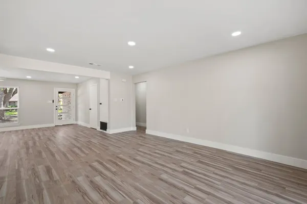 a view of an empty room with wooden floor and closet