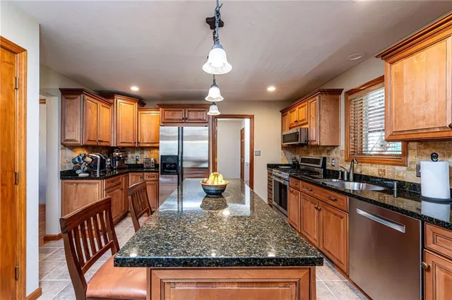 a kitchen with stainless steel appliances granite countertop a sink stove and refrigerator