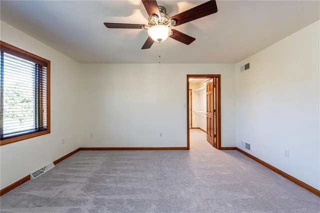 an empty room with ceiling fan and window