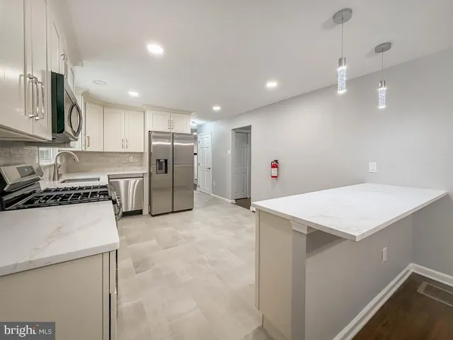 a kitchen with a refrigerator a sink and a stove top oven with wooden floor