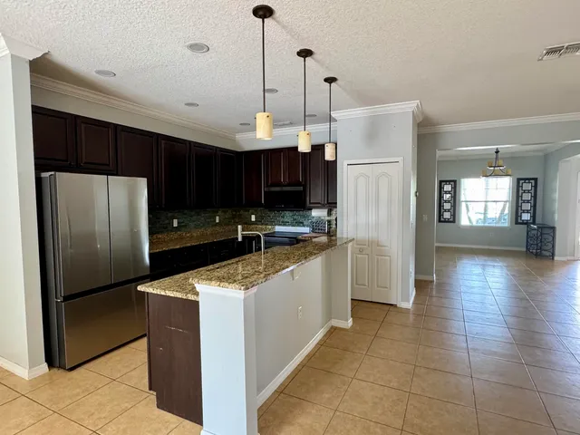 a kitchen with stainless steel appliances granite countertop a refrigerator a sink dishwasher a oven and a refrigerator with wooden floor