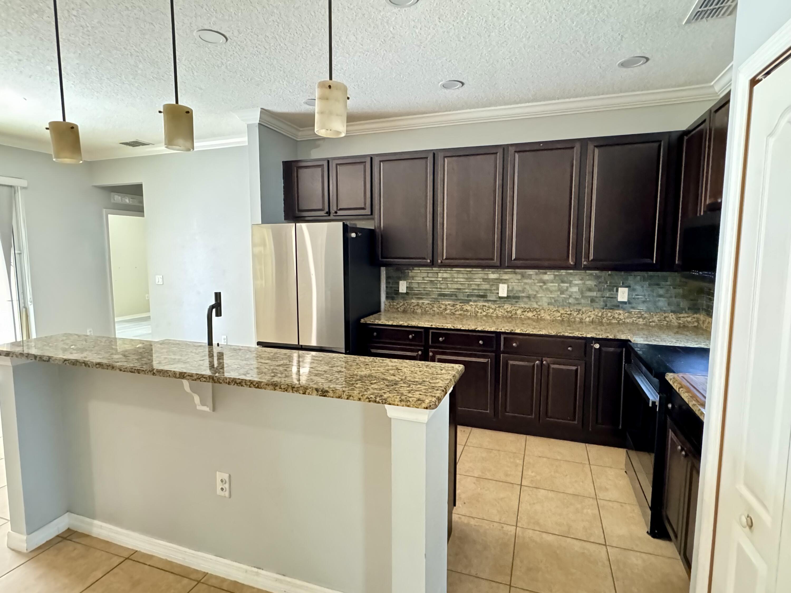 520 Southwest Dailey Avenue Port St. Lucie, FL 34953 - Photo 6 of 34 a kitchen with stainless steel appliances granite countertop a sink refrigerator and cabinets