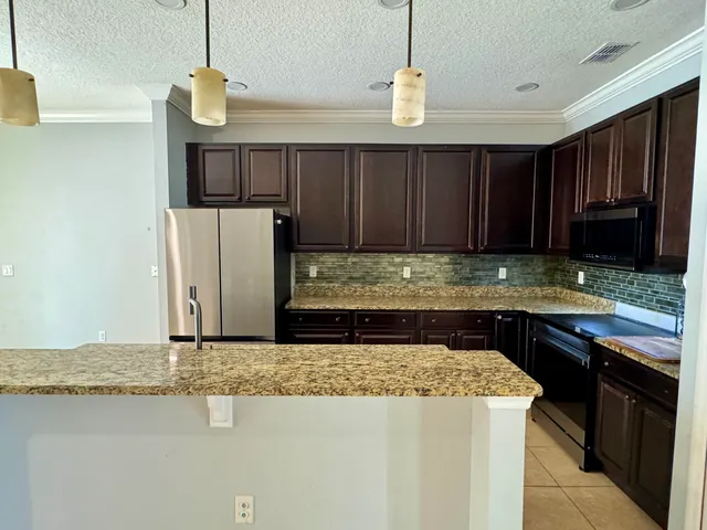 a kitchen with granite countertop wooden cabinets a sink a stove and a refrigerator