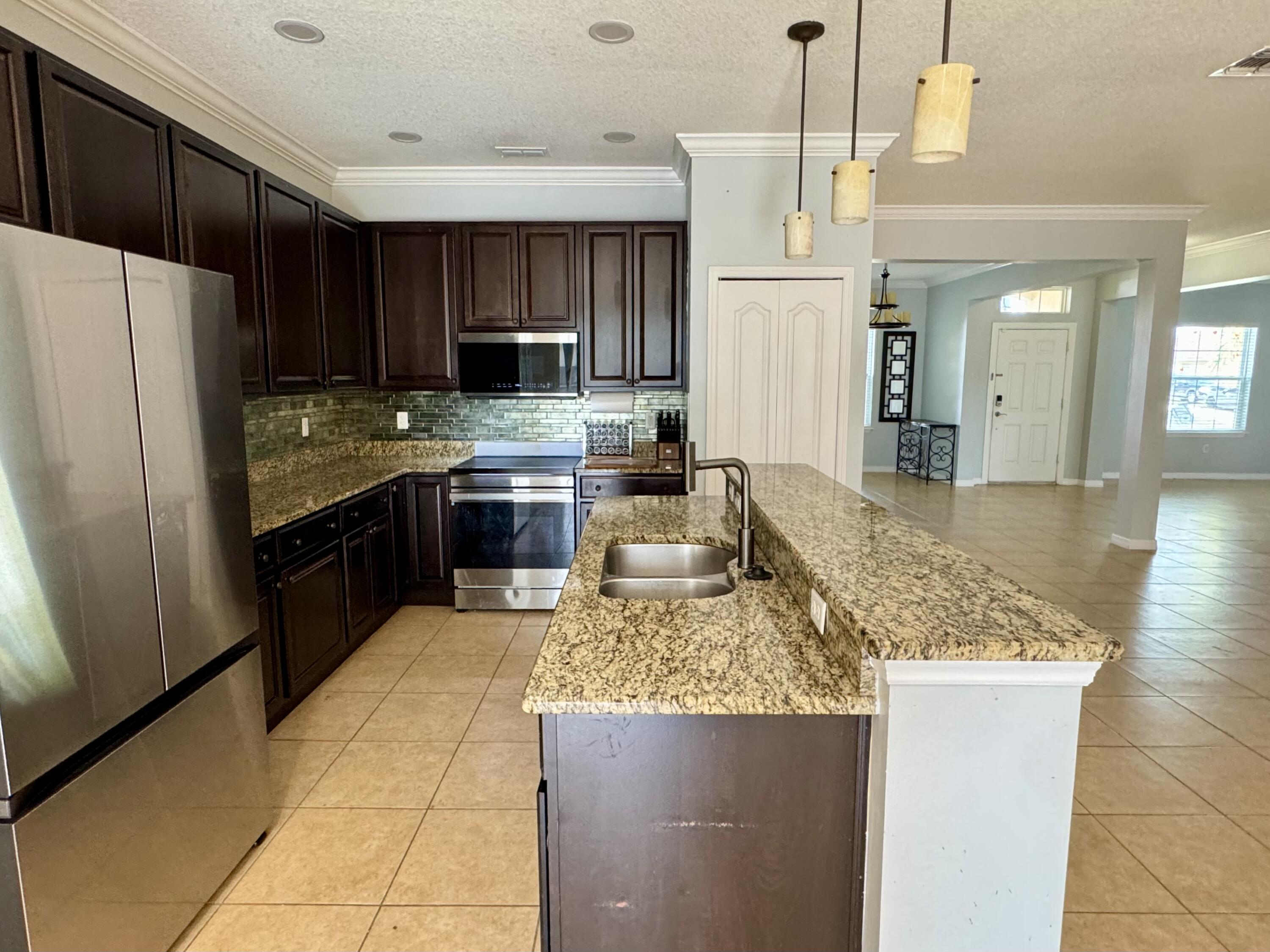 520 Southwest Dailey Avenue Port St. Lucie, FL 34953 - Photo 8 of 34 a kitchen with kitchen island granite countertop a refrigerator a stove and a sink