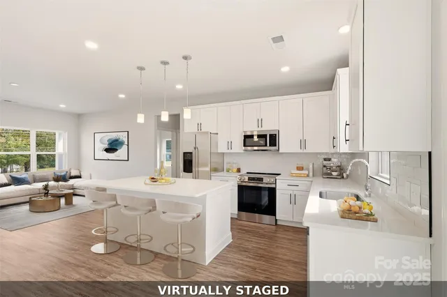 a large kitchen with stainless steel appliances kitchen island granite countertop a sink and a refrigerator