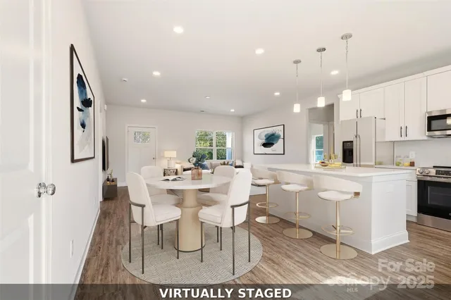 a large white kitchen with stainless steel appliances granite countertop a stove a sink a dining table and chairs