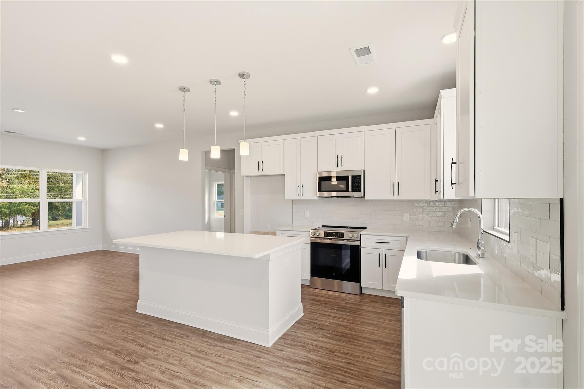 126 North Main Street Granite Falls, NC 28630 - Photo 9 of 34 a large kitchen with stainless steel appliances kitchen island granite countertop a stove a sink a refrigerator and white cabinets with wooden floor