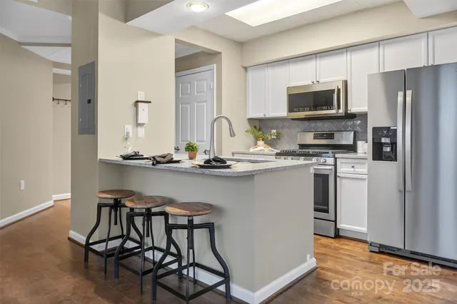 a kitchen with stainless steel appliances a table chairs microwave and refrigerator