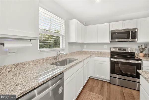 a kitchen with granite countertop a sink and steel appliances