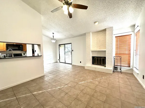 a view of a livingroom with a fireplace a ceiling fan and windows