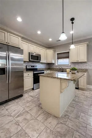 a kitchen with stainless steel appliances granite countertop a stove top oven a refrigerator a sink and a microwave