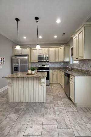 a kitchen with stainless steel appliances granite countertop a stove a sink dishwasher a refrigerator and white cabinets with wooden floor
