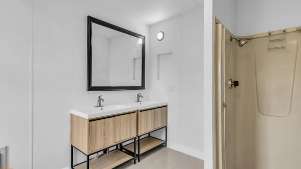 a bathroom with a double vanity sink mirror and shower