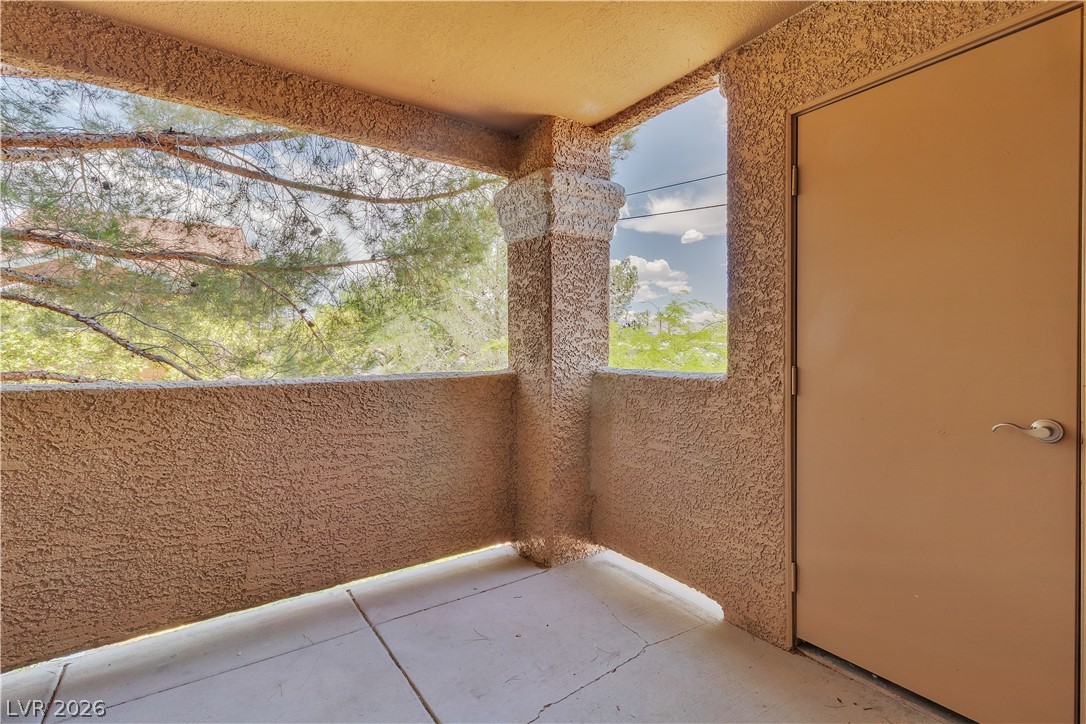 8101 West Flamingo Road, Unit 2001 Las Vegas, NV 89147 - Photo 16 of 28 An inviting private patio space with textured walls offers tranquil tree-lined views.