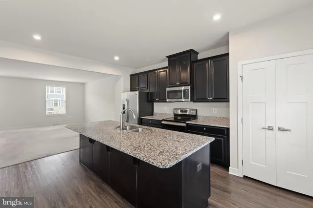 a kitchen with kitchen island granite countertop a sink and wooden cabinets