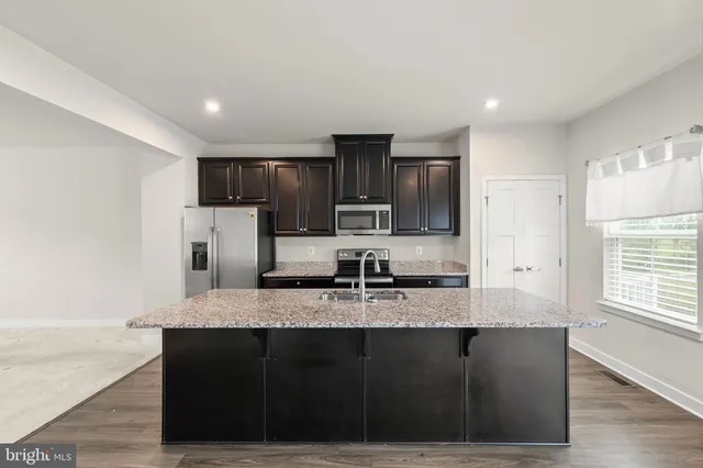 a kitchen with kitchen island granite countertop wooden cabinets and refrigerator
