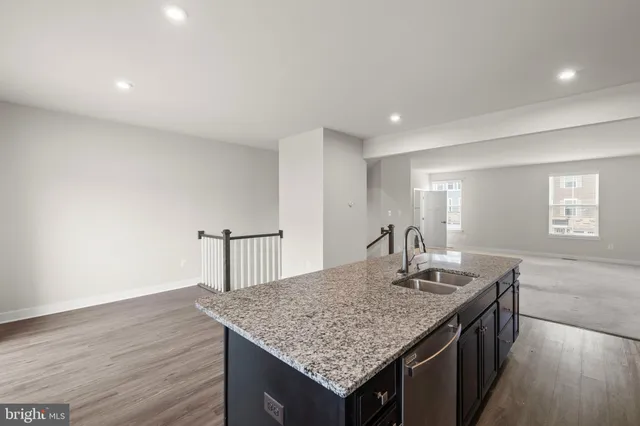 an open kitchen with granite countertop kitchen island a sink dishwasher a stove and a refrigerator with wooden floor