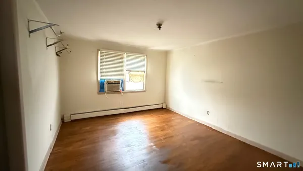 a view of an empty room with a window and wooden floor