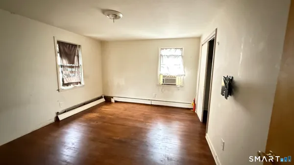 a view of an empty room with wooden floor and a window