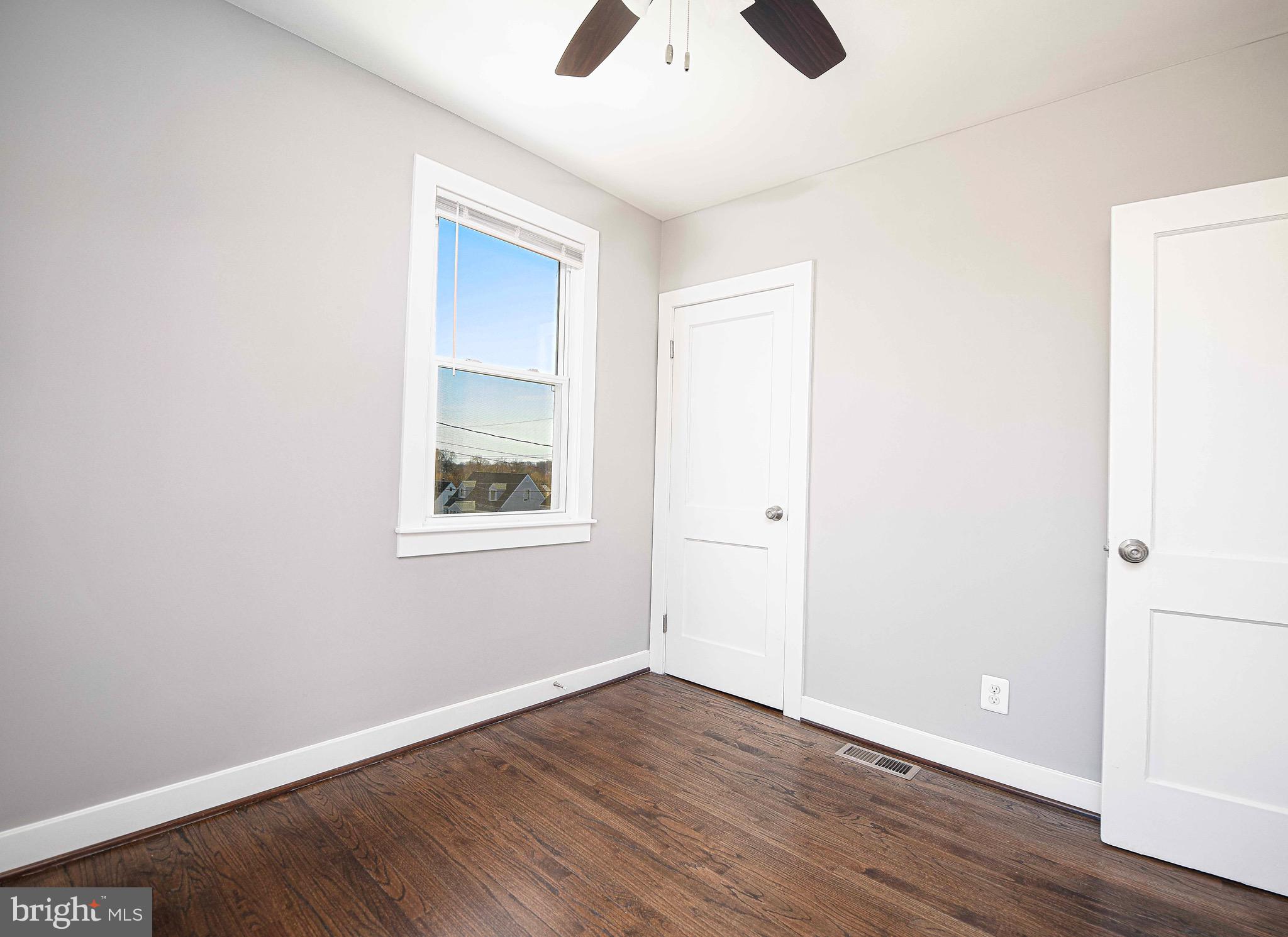 7906 31st Street Rosedale, MD 21237 - Photo 23 of 33 an empty room with wooden floor chandelier fan and windows