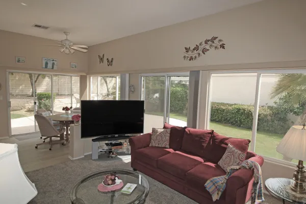 a living room with furniture a flat screen tv and a floor to ceiling window