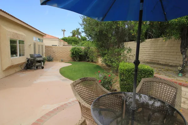 a view of a patio with table and chairs under an umbrella