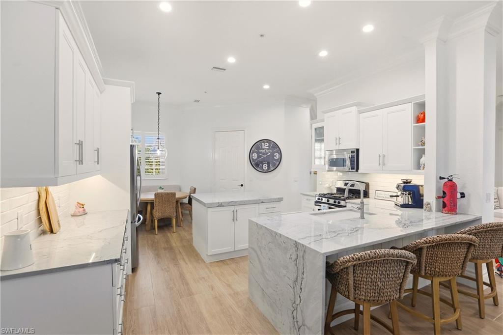 9263 Museo Circle, Unit 202 Naples, FL 34114 - Photo 14 of 50 a kitchen with a dining table chairs and white cabinets