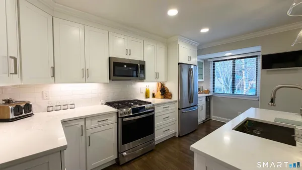 a kitchen with stainless steel appliances a stove a sink dishwasher a refrigerator and cabinets with wooden floor