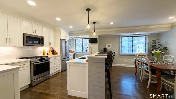 a kitchen with kitchen island a dining table chairs stainless steel appliances and cabinets