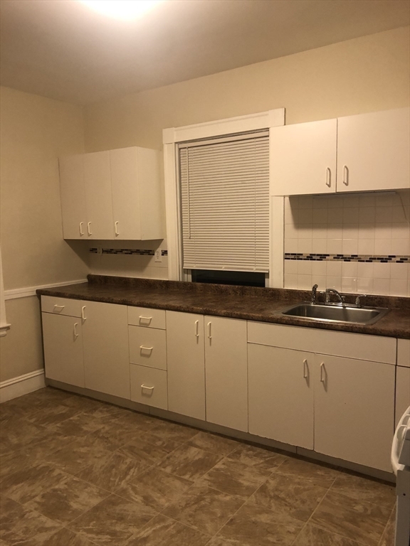 180 Lewis Street, Unit 2 Lynn, MA 01902 - Photo 7 of 14 a kitchen with granite countertop white cabinets and white appliances