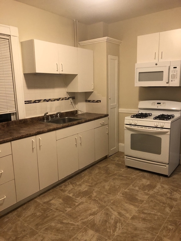 180 Lewis Street, Unit 2 Lynn, MA 01902 - Photo 9 of 14 a kitchen with stainless steel appliances granite countertop a stove a sink and a microwave