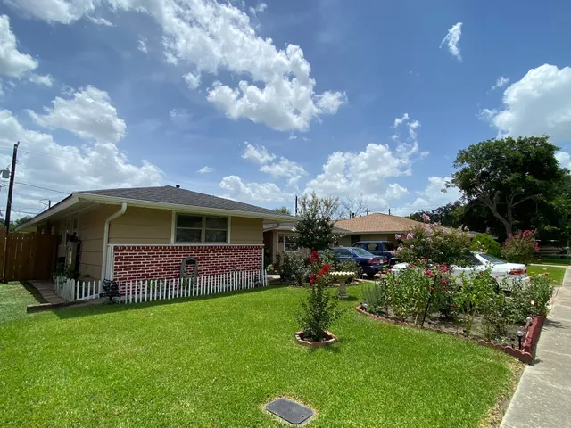 a front view of house with garden and trees