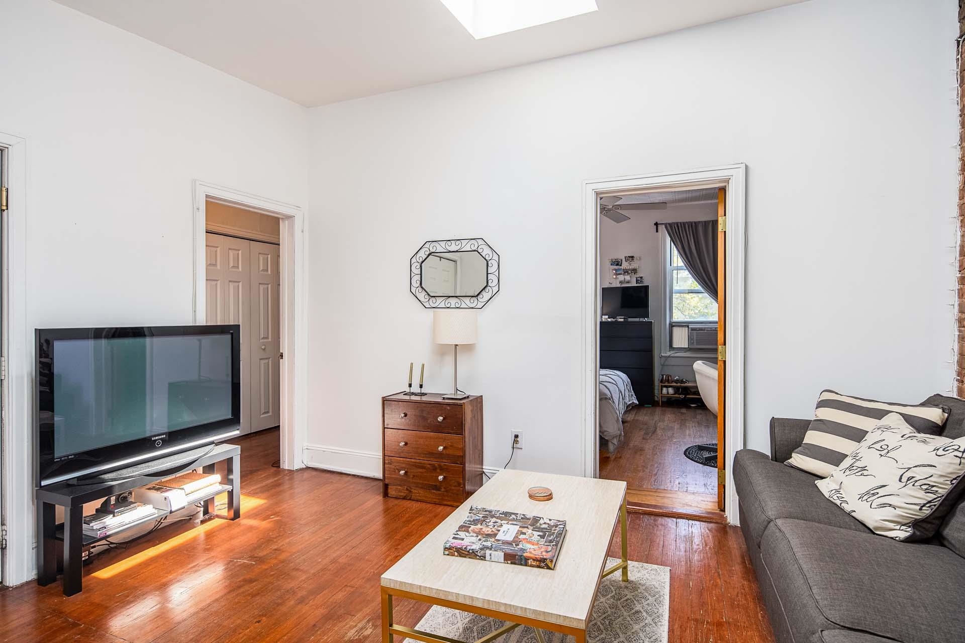 710 Bloomfield Street, Unit 3 Hoboken, NJ 07030 - Photo 4 of 13 a living room with furniture a flat screen tv and a fireplace
