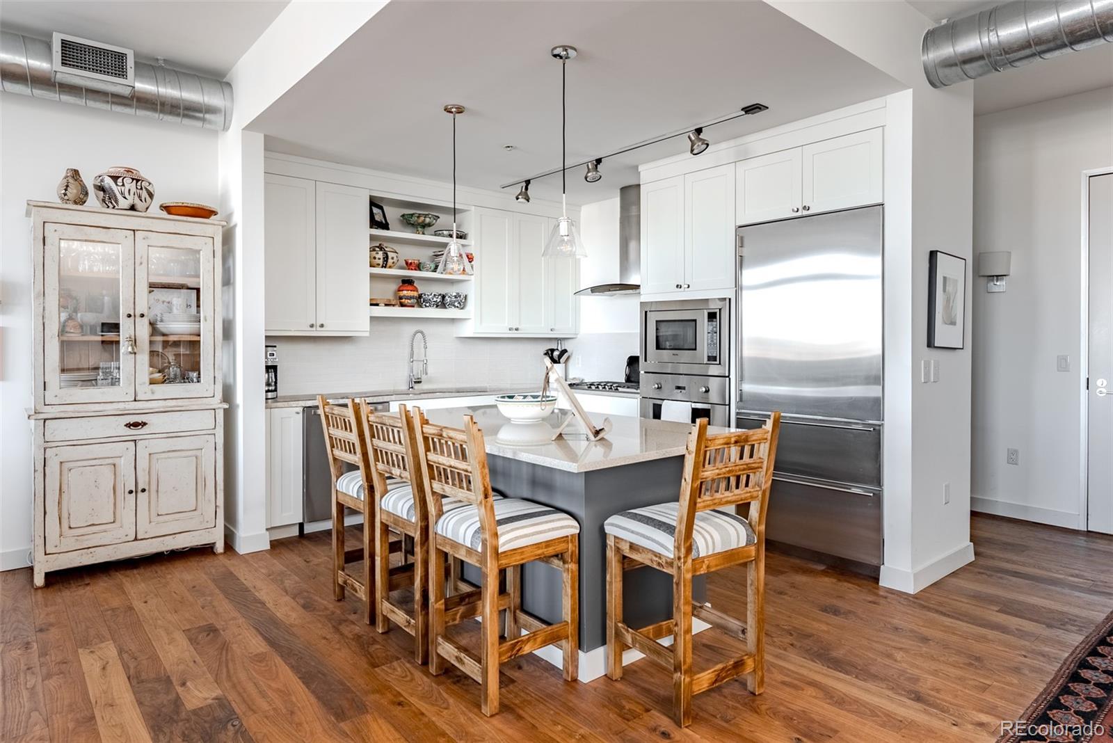 2229 Blake Street, Unit 709 Denver, CO 80205 - Photo 5 of 40 a kitchen with stainless steel appliances kitchen island granite countertop a table chairs refrigerator and microwave