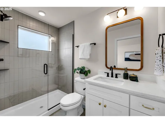 a bathroom with a toilet a sink a glass door a shower a mirror and vanity