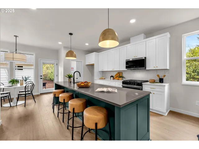 a kitchen with stainless steel appliances granite countertop a stove top oven a sink a dining table and chairs with wooden floor