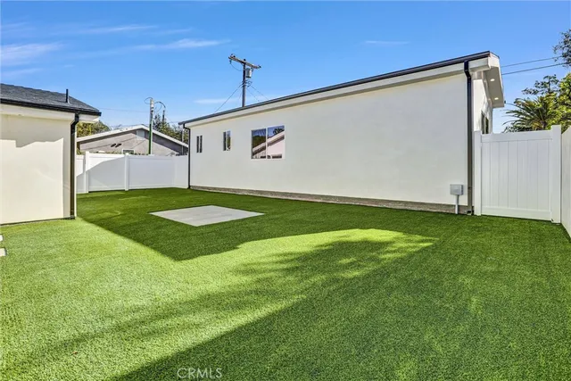a view of an empty room with wooden floor and a kitchen